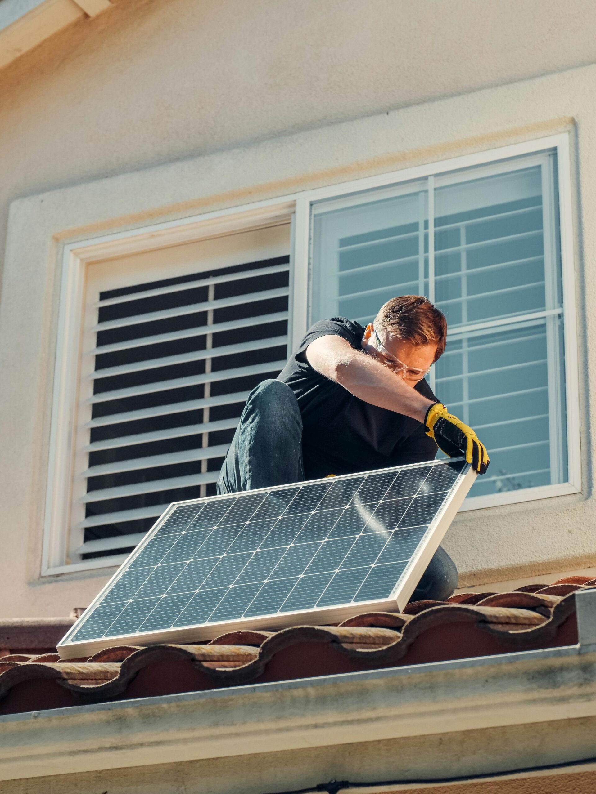 Solar installer fitting a rooftop solar panel on a residential property in Northern Ireland